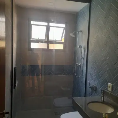Box de vidro com perfil preto em banheiro de azulejo azul