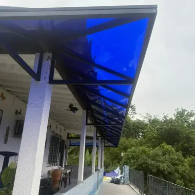 Cobertura de policarbonato azul sobre varanda com corredor lateral