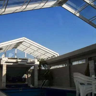Telhado retrátil transparente em módulos sobre a piscina, com estrutura branca